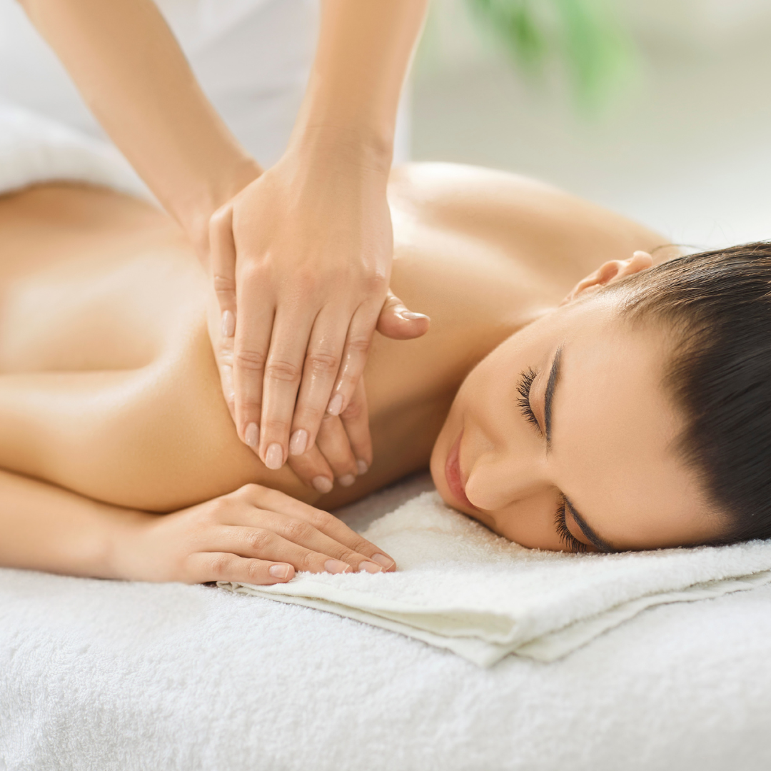 Woman resting peacefully on a massage table while receiving a soothing shoulder and back massage
