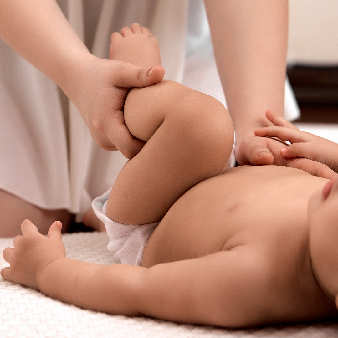 Parent's hands gently bicycling a baby's legs during an infant massage instruction session